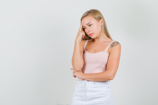 Jeune femme regardant vers le bas avec le doigt sur le front en maillot