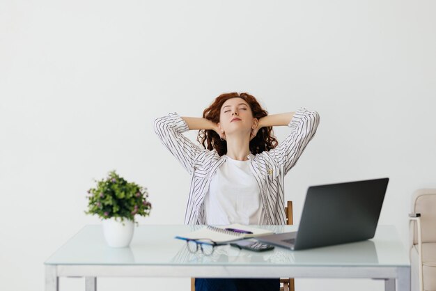 Jeune femme relaxante avec ses mains derrière sa tête et assise sur une chaise