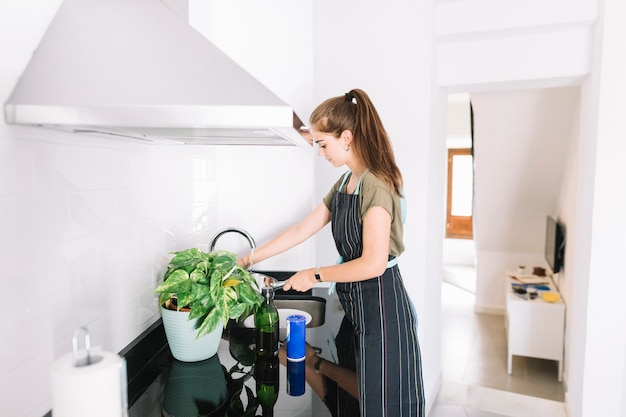 Photo gratuite jeune femme remplissant d'eau dans une casserole dans la cuisine