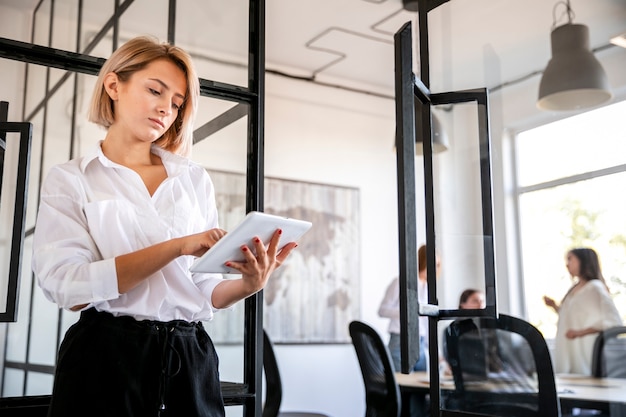 Jeune femme à la réunion à l'aide de tablette