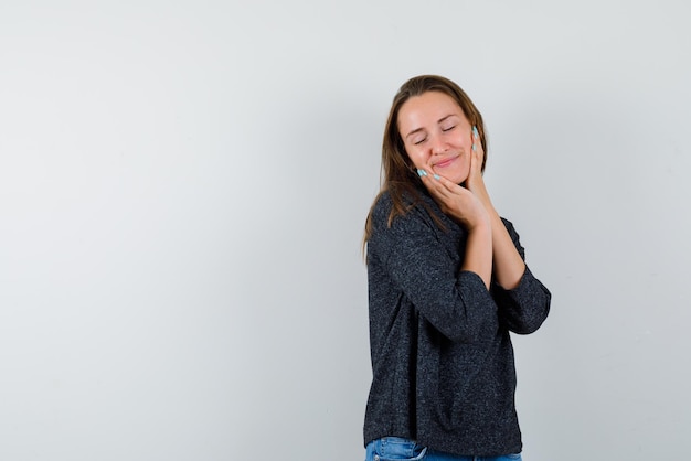 La jeune femme rêve en mettant ses mains sur les joues sur fond blanc