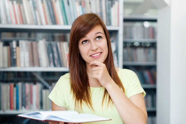 Jeune femme, rêverie, dans, bibliothèque