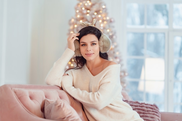 Jeune femme en robe blanche sur le canapé à Noël