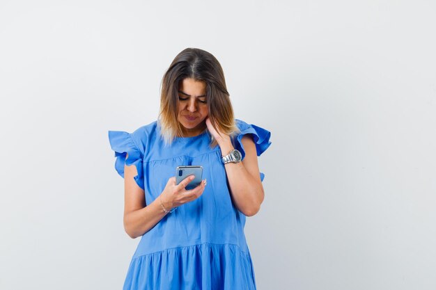 Jeune femme en robe bleue utilisant un téléphone portable et ayant l'air occupé