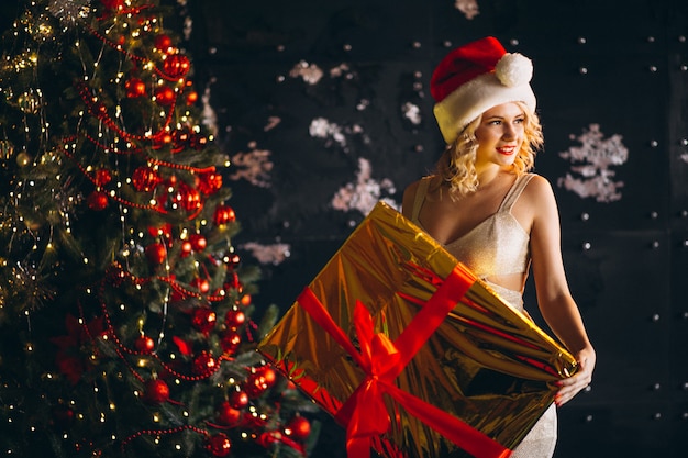 Photo gratuite jeune femme en robe avec des cadeaux de noël par sapin de noël