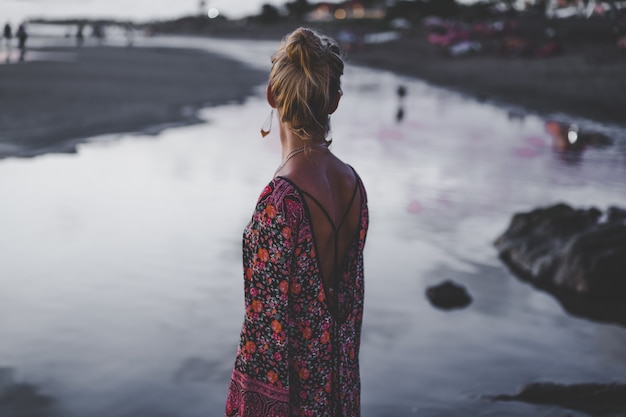 jeune femme en robe de couleur sur la côte de l&#39;océan au coucher du soleil