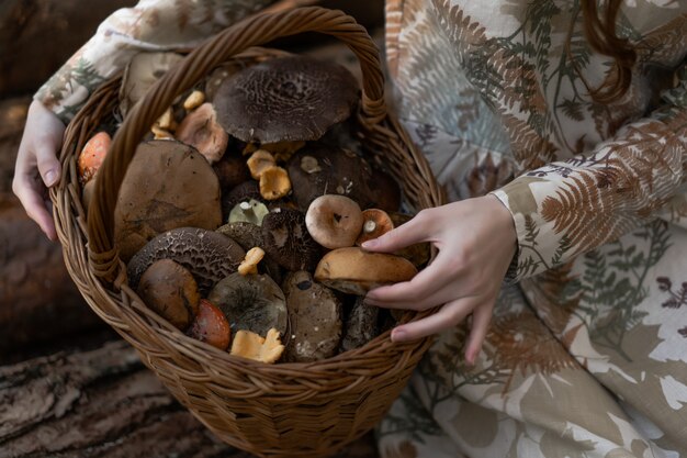 Jeune femme en robe de lin ramassant des champignons dans la forêt