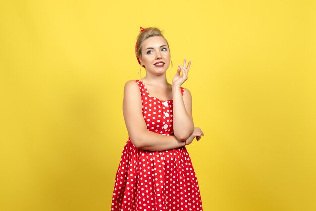 Jeune femme en robe à pois rouge debout et posant sur le sol jaune femme femme couleur jolie robe fashion