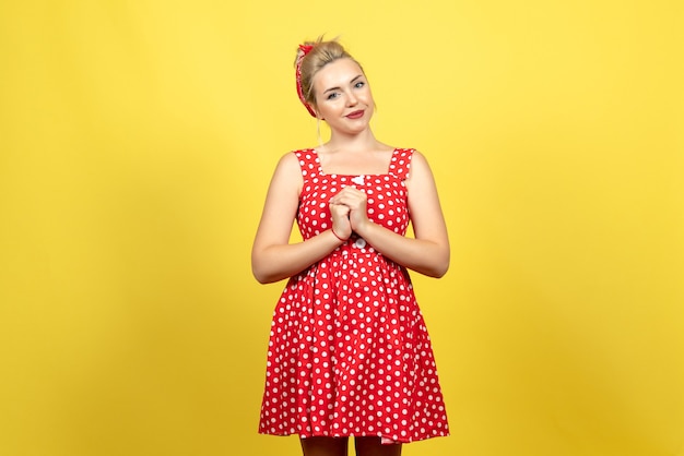 Jeune femme en robe à pois rouge juste debout sur jaune