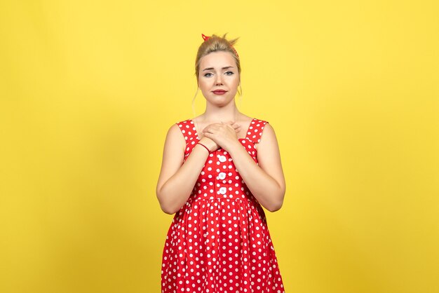 jeune femme en robe à pois rouge posant sur jaune