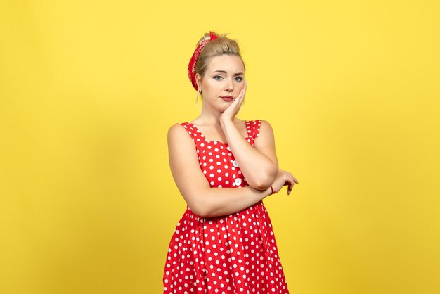 jeune femme en robe à pois rouge posant sur jaune