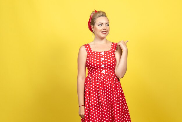 jeune femme en robe à pois rouge posant sur jaune