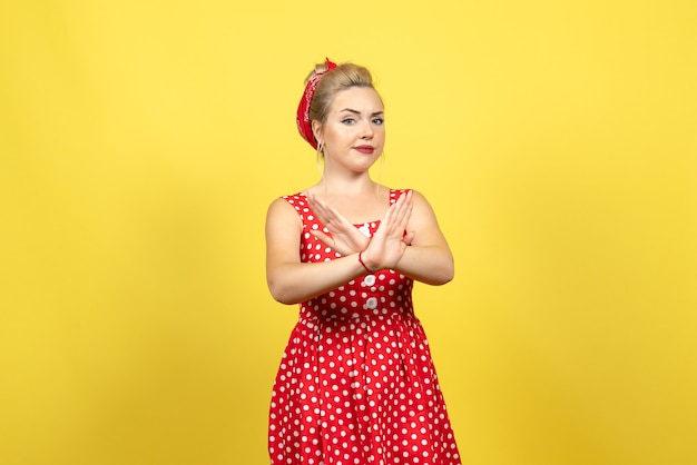 Photo gratuite jeune femme en robe à pois rouge posant sur jaune