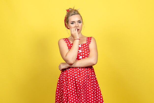 jeune femme en robe à pois rouge posant sur jaune