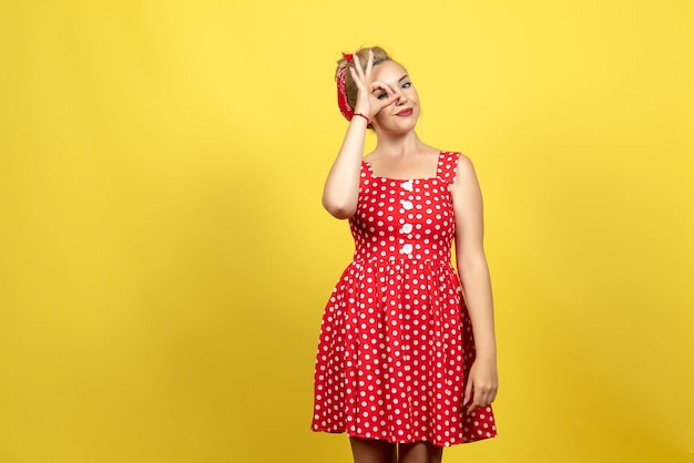 Photo gratuite jeune femme en robe à pois rouge posant sur le sol jaune robe femme mode ancienne couleur rétro