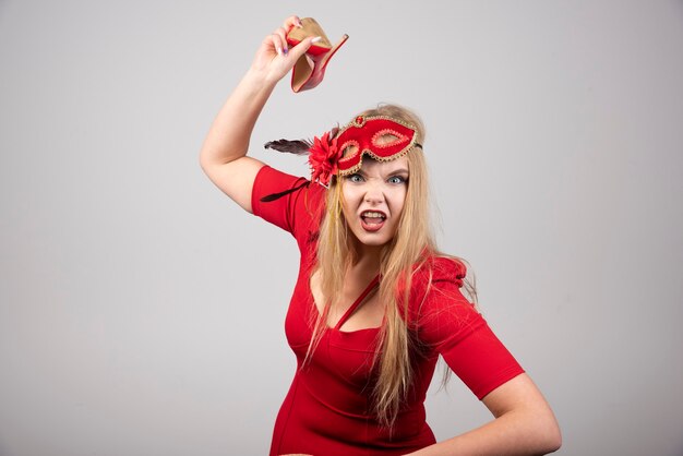 Jeune femme en robe rouge jetant son talon.