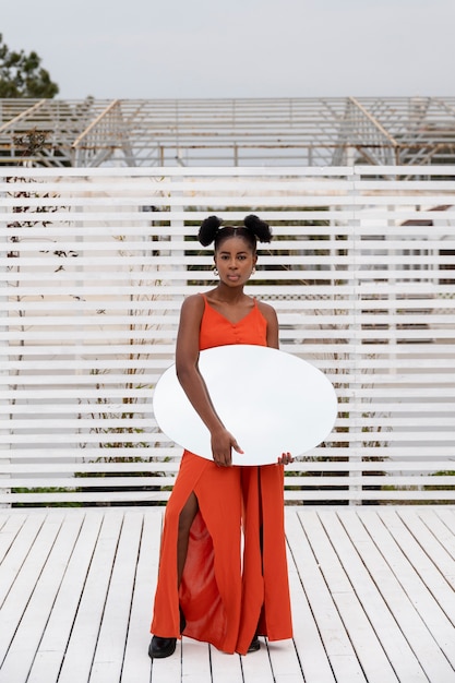 Jeune femme avec une robe rouge posant à l'extérieur avec miroir