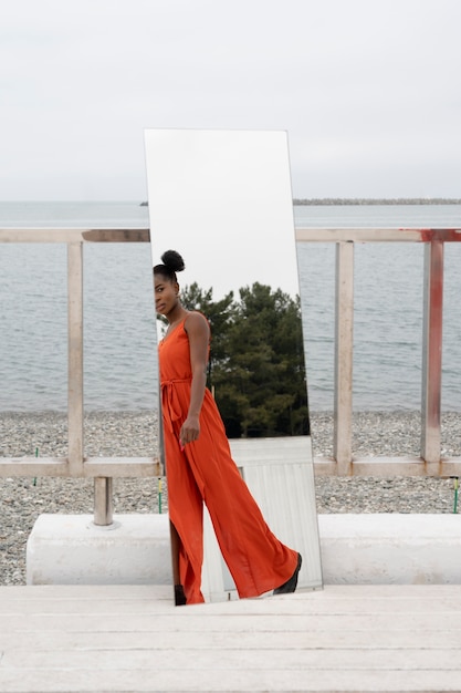 jeune femme, à, robe rouge, poser, dehors, dans, miroir