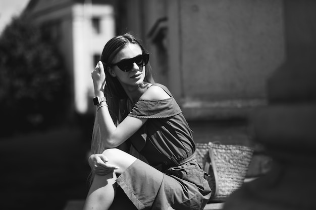 Jeune femme en robe verte assise sur les marches d'un immeuble ancien