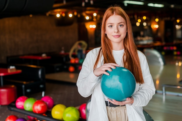 Jeune femme rousse tenant une boule de bowling turquoise