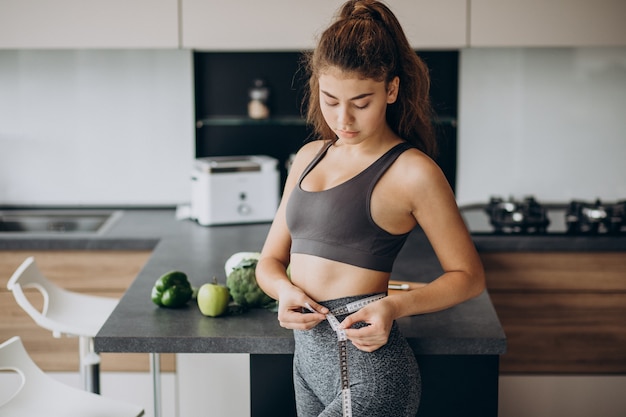 Jeune femme avec ruban à mesurer sur weist à la cuisine