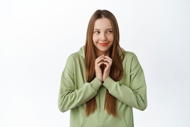 Photo gratuite une jeune femme rusée a un plan intéressant, des doigts de clocher comme intrigants et regardant de côté, réfléchissez à un schéma, debout sur un mur blanc