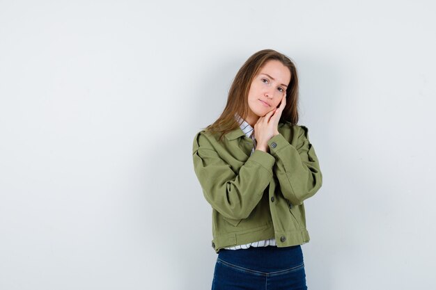 Jeune femme s'appuyant sur les paumes comme oreiller en chemise et très jolie. vue de face.