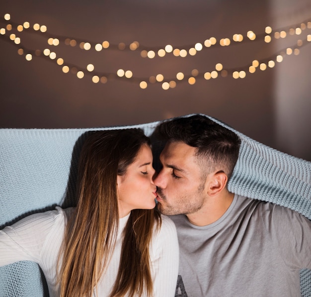 Photo gratuite jeune femme s'embrassant avec un mec en couvre-lit