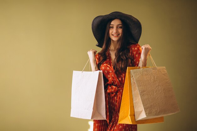 Jeune femme avec des sacs dans une belle robe et un chapeau