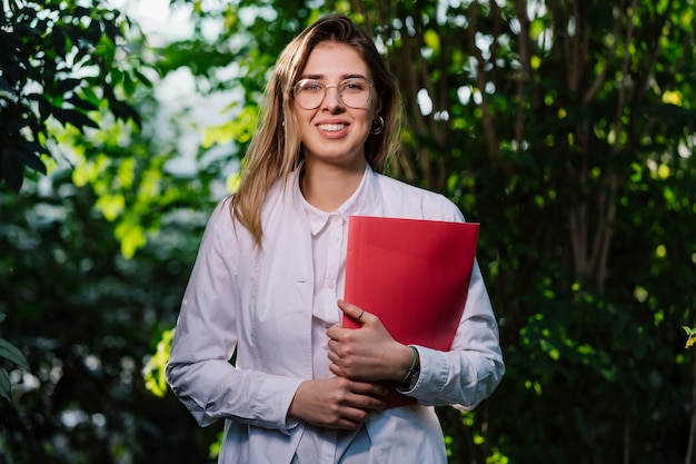 Jeune femme scientifique posant avec dossier rouge