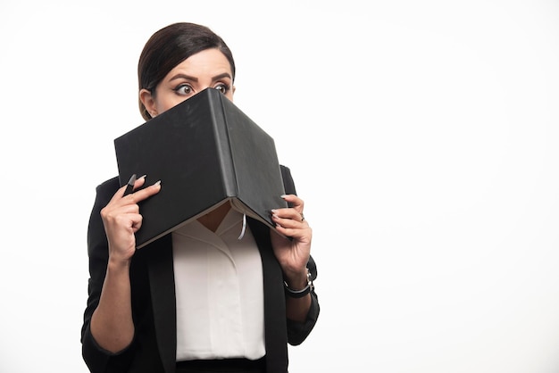 Jeune femme se cachant derrière un livre sur fond blanc. photo de haute qualité