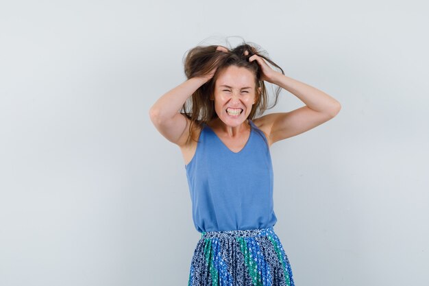 Jeune femme se déchirant les cheveux en maillot, jupe et l'air excité. vue de face.