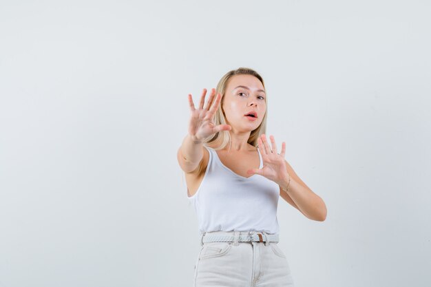 Jeune femme se défendant de quelque chose en chemisier blanc et l'air anxieux. . espace pour le texte