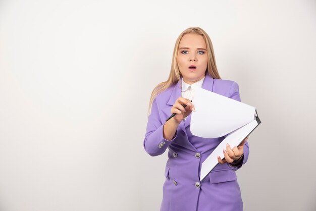 Jeune femme se demandant avec un crayon et une tablette sur blanc.