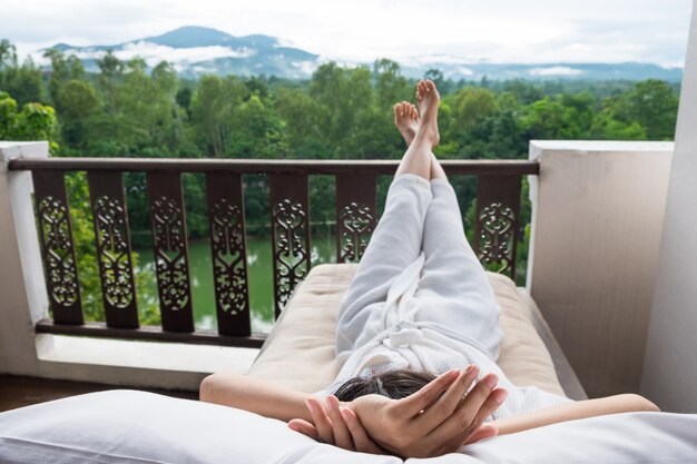 Une jeune femme se détend sur le lit et profite de la vue sur la montagne