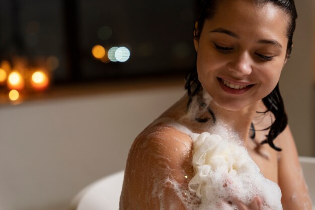 Jeune femme se lavant à l'aide d'une éponge de bain