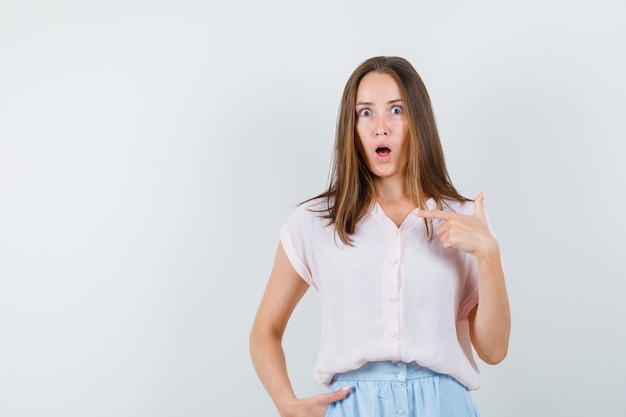 Jeune femme se montrant en t-shirt, jupe et à la choqué. vue de face.