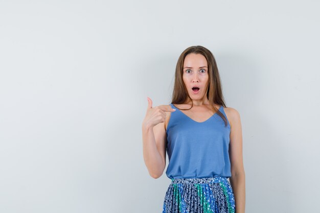 Jeune femme se pointant en maillot, jupe et l'air perplexe. vue de face.