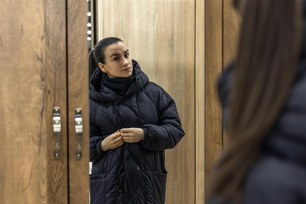 Une jeune femme se regarde dans un miroir de placard