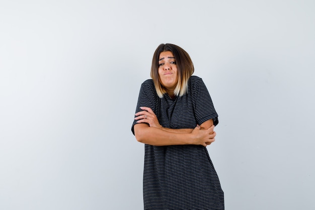 Jeune femme se serrant dans une robe polo et à la nostalgie. vue de face.