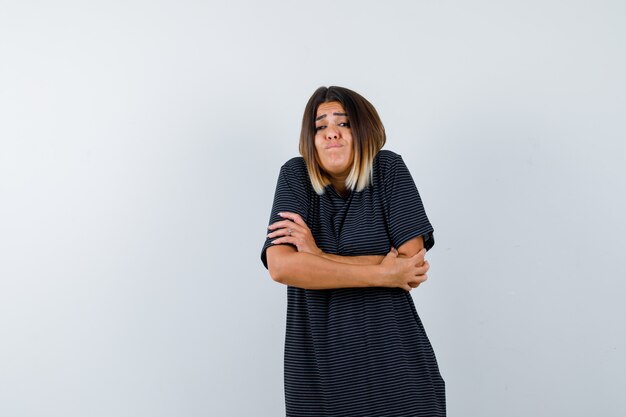 Jeune femme se serrant dans une robe polo et à la nostalgie. vue de face.