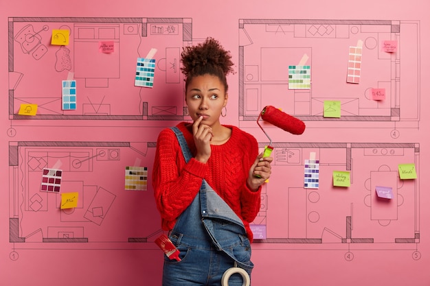 Jeune femme se tient à côté de l'esquisse de conception de maison prête pour la rénovation