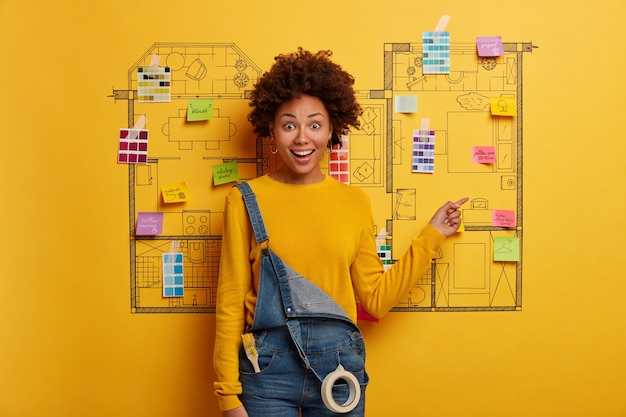 Jeune femme se tient à côté de l'esquisse de conception de maison prête pour la rénovation