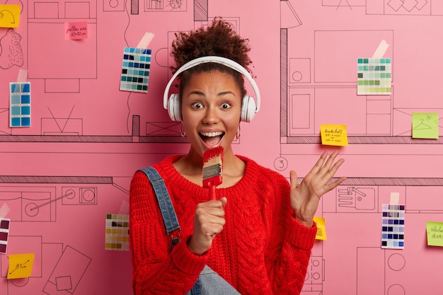 Jeune femme se tient à côté de l'esquisse de conception de maison prête pour la rénovation