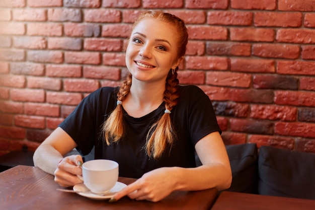 Jeune femme, séance, dans, café, contre, mur brique