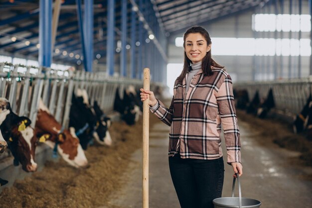 Jeune femme avec seau et à l'étable nourrir les vaches