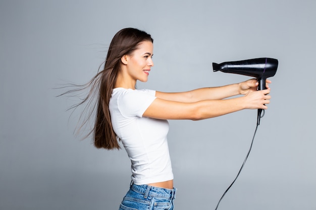 Jeune femme séchant les cheveux longs avec ventilateur électrique isolé sur blanc