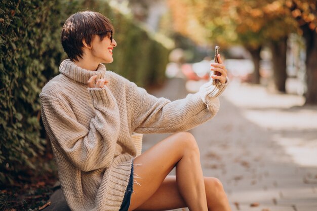 Jeune femme séduisante à l'aide de téléphone