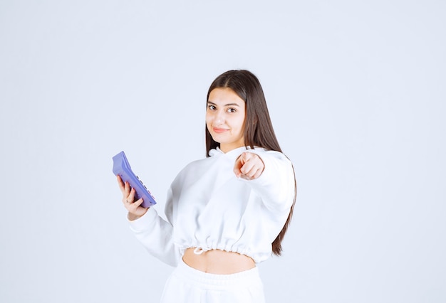 Une jeune femme séduisante avec une calculatrice électronique pointant vers la caméra.