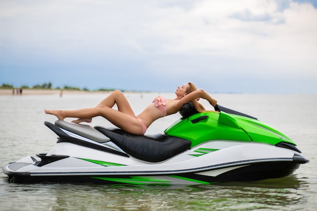 Jeune femme séduisante avec un corps mince en maillot de bain bikini élégant s'amusant sur un scooter des mers, vacances d'été, sport actif